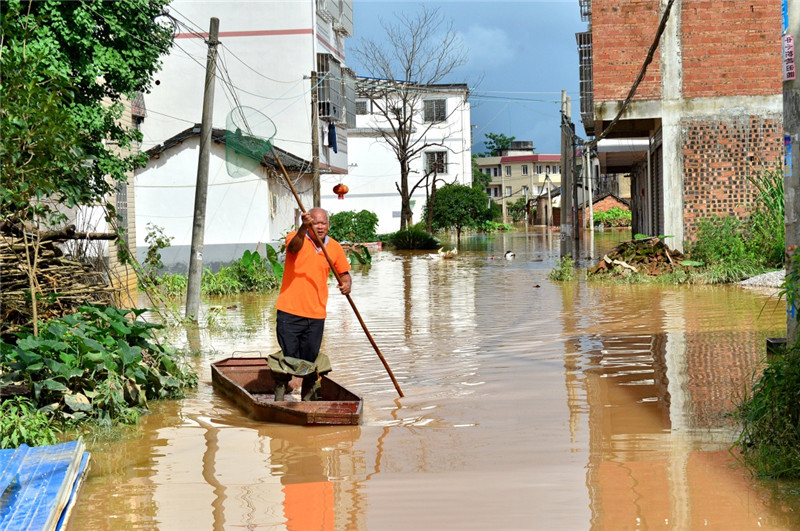 7月3日，桂林市雁山區雁山鎮的一名村民撐船駛出被洪水淹沒的村莊。
