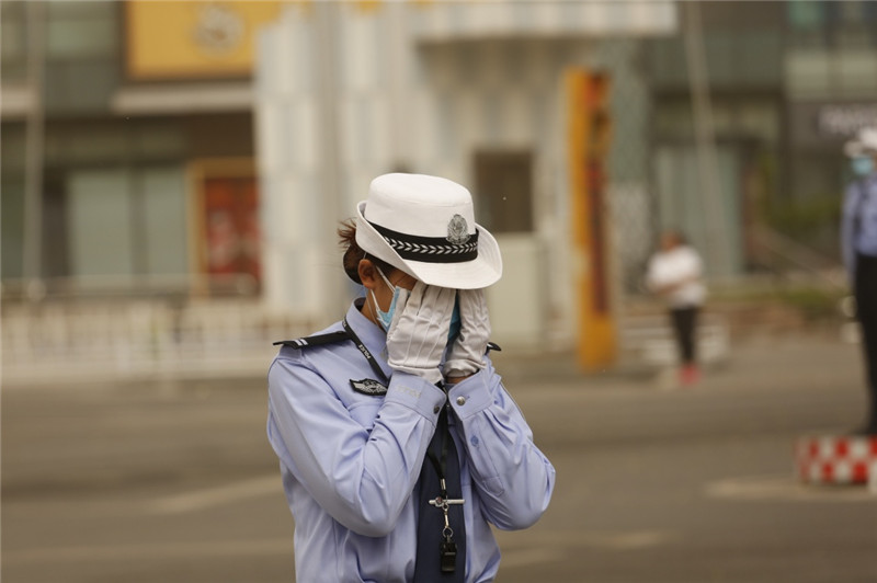 5月5日，在河北省廊坊市街頭，一名交警掩面躲避風沙。