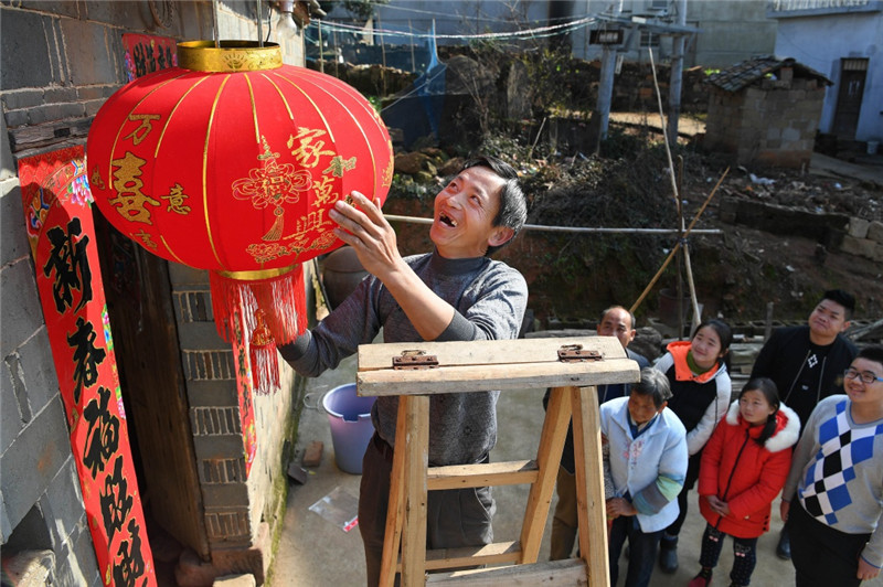 江西鄱陽縣古縣渡鎮張家坽村村民張雪運（左一）在家門口掛燈籠，喜迎新春佳節（1月24日攝）。