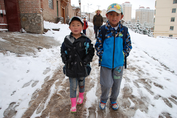 5月26日，小朋友走在甘肅甘南藏族自治州合作市雪后濕滑的道路上。新華社發（后志良 攝）