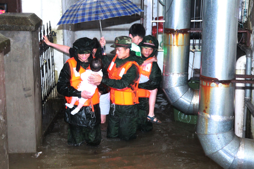 7月3日，武警銅陵市支隊官兵在轉移被困群眾。連日來，受強降雨影響，安徽省銅陵市郊區大通鎮一小區發生內澇，77名群眾被困。7月3日凌晨，武警銅陵市支隊25名官兵深入內澇小區將被困群眾轉移到安全地帶。新華社發（繆衛立攝）