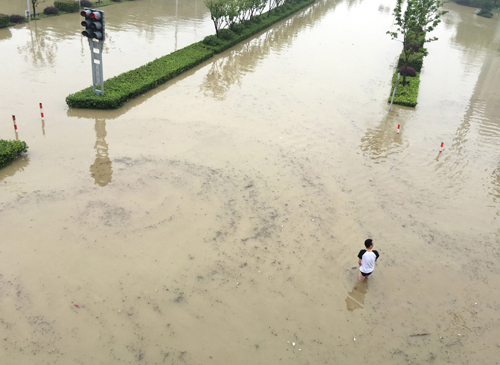 7月3日，江蘇無錫一名市民在被暴雨淹沒的道路上涉水前進。中央氣象臺7月3日18時繼續發布暴雨橙色預警，預計3日20時至4日20時，安徽中南部、江蘇中南部、湖北東南部、江西西北部、湖南北部和西部、貴州東南部、廣西北部等地有暴雨，其中，安徽和江蘇兩省沿江地區、湖北東南部、湖南東北部及西部、貴州東南部等地的部分地區有大暴雨；上述地區伴有短時強降水和雷暴大風等強對流天氣。新華社發