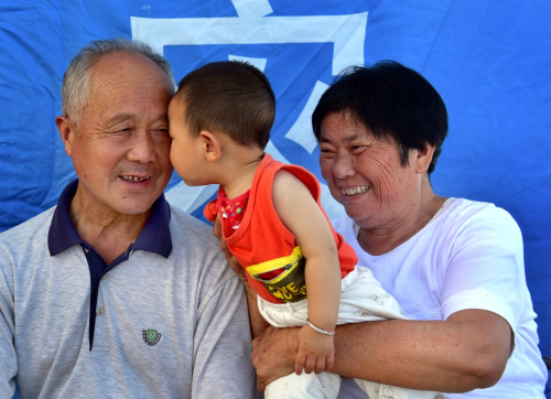 7月6日，劉傳德夫婦在舒城縣柏林職高安置點的帳蓬里與孫子逗樂。新華社發（張向陽 攝