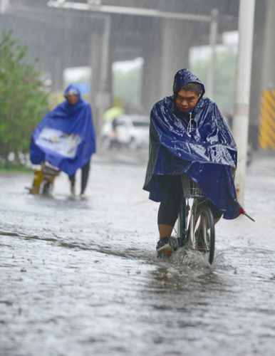 7月20日，一位石家莊市民在槐安路冒雨涉水騎行。