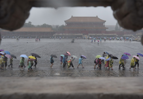 7月20日，游客冒雨在北京故宮游覽。