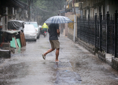 7月20日，行人在北京溫家街胡同冒雨前行。
