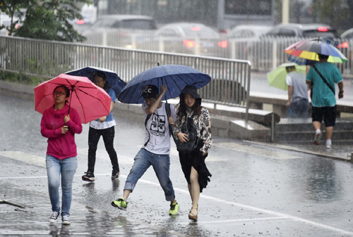 7月20日，行人在北京羊坊店路上冒雨前行。