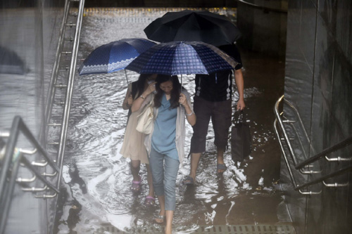 7月20日，行人在北京羊坊店路一個地下通道涉水通過。