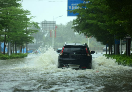 10月18日，一輛汽車在海南瓊海街頭的積水中行駛。
