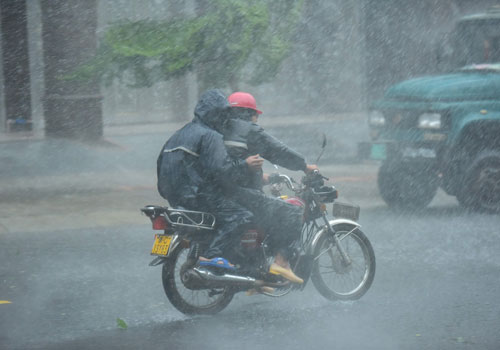 10月18日，在海南瓊海街頭，人們在暴雨中出行。