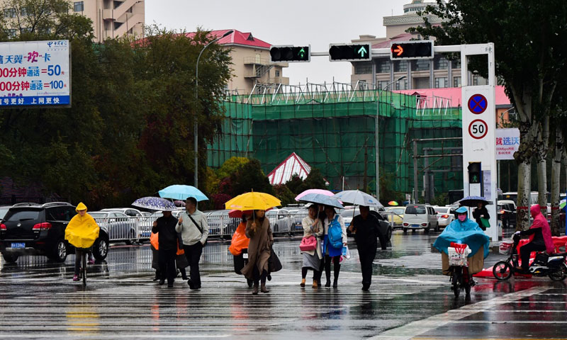 10月27日，在呼和浩特街頭，行人在雨中通過斑馬線。