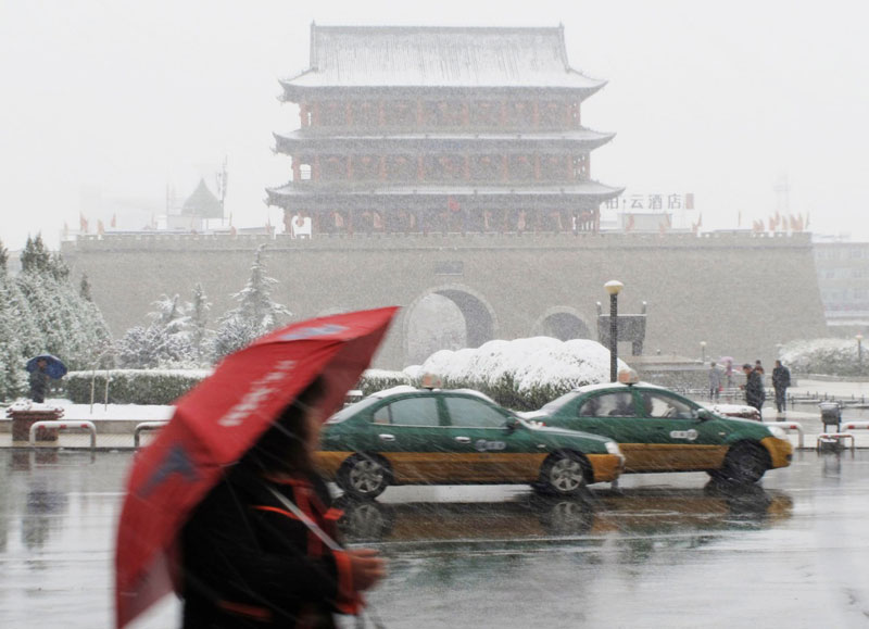 10月27日，車輛和行人冒雪在武威街頭行進。