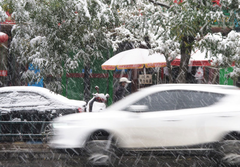 10月27日，車輛和行人冒雪在武威街頭行進。