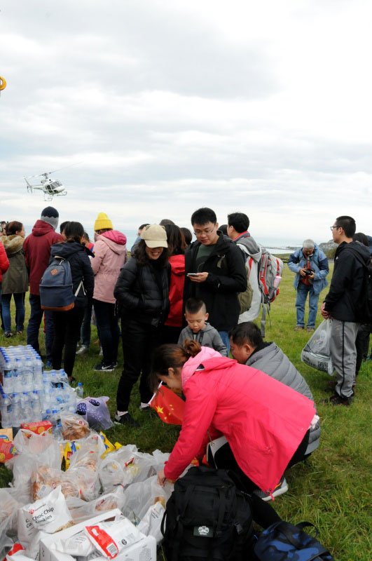  11月14日，在新西蘭凱伊庫拉小鎮，地震受困游客領取總領事館空運來的食品和瓶裝水，等待直升機分批救援。