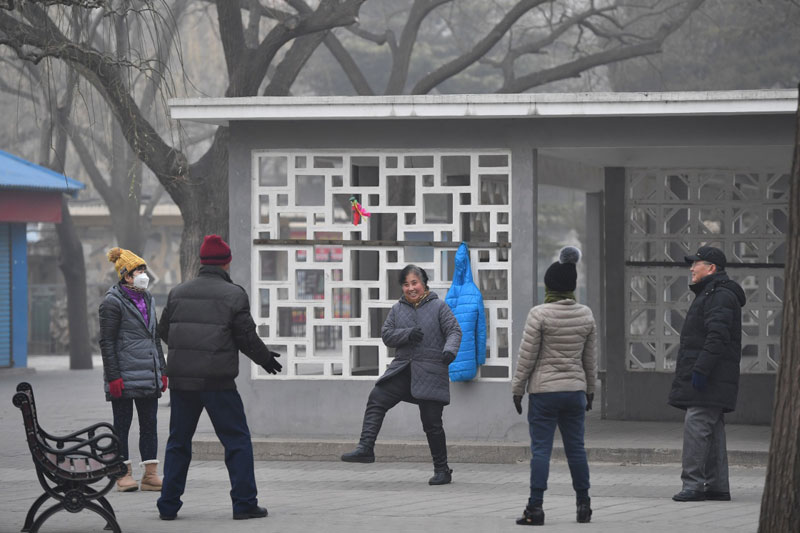 12月21日，幾名市民在霧霾籠罩的陶然亭公園內踢毽子。