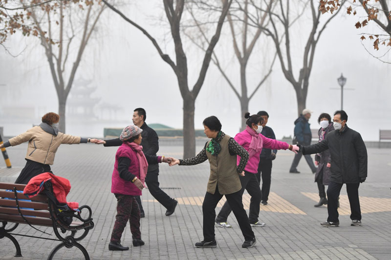 12月21日，市民在霧霾籠罩的陶然亭公園內跳舞。