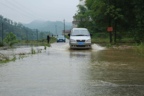 5月19日，在湖南省邵陽市隆回縣三閣司鎮，汽車通過被淹洼地。新華社發（曾勇 攝）